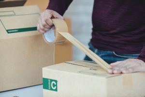 Mężczyzna zakleja pudełko. Pakowanie paczek - jak powinno wyglądać