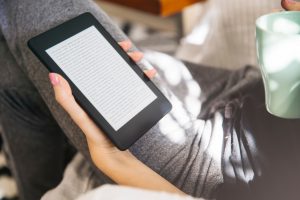 Kobieta czyta książkę na czytniku ebooków. Ebook czy książka papierowa - co jest bardziej eko