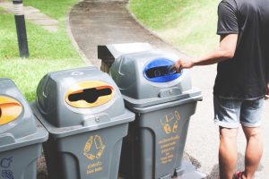Mężczyzna wrzuca plastikową butelkę do pojemnika