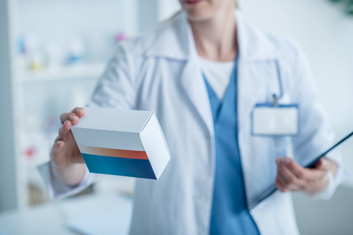 Lekarka trzyma pudełko leków. Opakowania z tektury dla branż przemysłowych - branża chemiczna i farmaceutyczna 